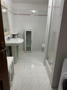 ein weißes Bad mit einem Waschbecken und einer Dusche in der Unterkunft Comfort House in Olbia
