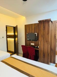 a hotel room with a bed and a desk with a tv at Airport Hotel Relax Inn in Nagpur
