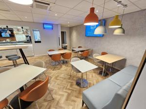 a dining room with tables and chairs and lights at ibis budget Derby in Derby