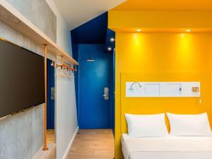 a bedroom with a blue and yellow wall at ibis budget Patos de Minas in Patos de Minas