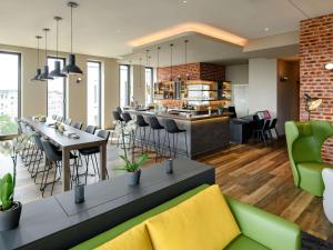 a restaurant with a bar with chairs and tables at Aparthotel Adagio Bremen City in Bremen