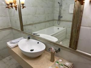 uma casa de banho com um lavatório, um espelho e uma banheira em Royal em Aqtöbe