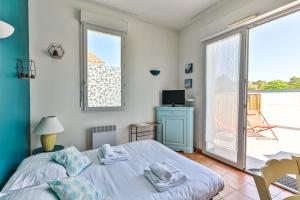 a bedroom with a bed and a large window at Résid'Azur - T2 résidentiel avec piscine in Saint-Jean-de-Monts