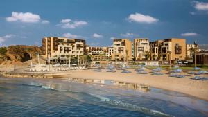 a beach with chairs and umbrellas and buildings at Kempinski Summerland Hotel & Resort Beirut in Beirut