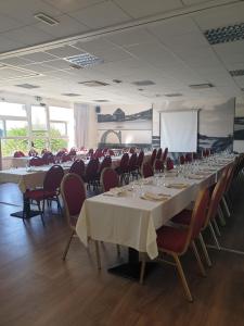 a conference room with tables and chairs and a screen at Logis Hôtel Lucotel in Lanvollon