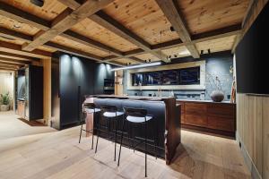 a kitchen with wooden ceilings and a bar with stools at Chalet Strandafjellet in Stranda