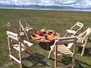 3 Stühle und ein Tisch mit Obst auf einem Feld in der Unterkunft Tunduk son-kol yurt camp in Song-Kul