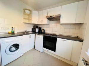 a kitchen with white cabinets and a washer and dryer at Central City West in Berlin