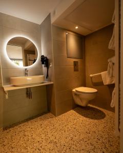 a bathroom with a toilet and a sink and a mirror at Kyriad Lyon Sud Sainte Foy in Sainte-Foy-lès-Lyon