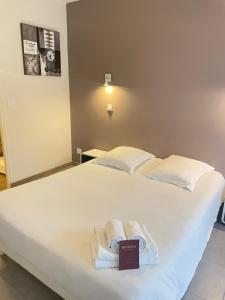 - un grand lit blanc avec des serviettes dans l'établissement Hôtel Némo Aéroport de Pau - KB HOTEL GROUP, à Sauvagnon