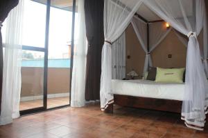 ein Schlafzimmer mit einem Himmelbett und einem großen Fenster in der Unterkunft HOTEL LE GRAND PALAIS in Fianarantsoa