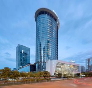 a tall glass building in a city at Kempinski Hotel Taiyuan in Taiyuan