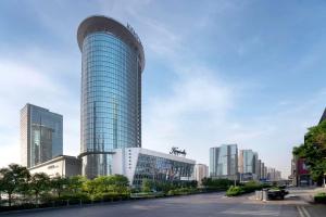 a tall glass building in a city with tall buildings at Kempinski Hotel Taiyuan in Taiyuan