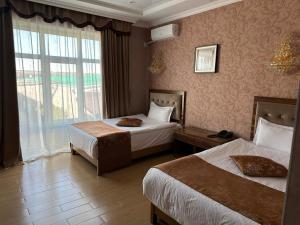 Habitación de hotel con 2 camas y ventana en Royal, en Aktobe