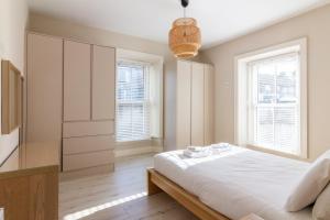 a white bedroom with a bed and two windows at GuestReady - Relax and Explore in Dundrum in Dublin