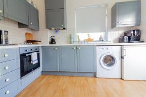 eine Küche mit blauen Schränken, einer Waschmaschine und einem Trockner in der Unterkunft GuestReady - Tranquil retreat in Chapelizod in Dublin