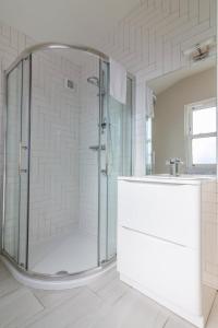 a white bathroom with a shower and a sink at GuestReady - Relax and Explore in Dundrum in Dublin