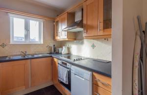 uma cozinha com armários de madeira e uma máquina de lavar louça branca em GuestReady - Castle Proximity and Modern Charm em Dublin