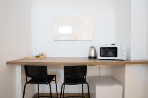 a kitchen counter with two bar stools and a microwave at La Pigna in Bari +47 photos