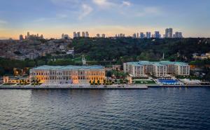 a large building on the water with a city at Çırağan Palace Kempinski Istanbul in Istanbul