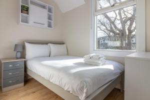 - une chambre blanche avec un lit et une fenêtre dans l'établissement GuestReady - Cosy Retreat in Donnybrook, à Dublin