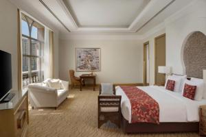 um quarto de hotel com uma cama grande e uma cadeira em Marsa Malaz Kempinski, The Pearl em Doha