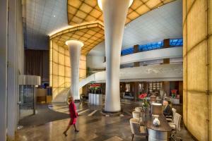 a woman walking through a lobby of a building at Kempinski Hotel Corvinus Budapest in Budapest