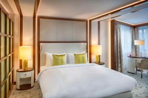 1 dormitorio con 1 cama blanca grande y 2 lámparas en Kempinski Hotel Corvinus Budapest en Budapest