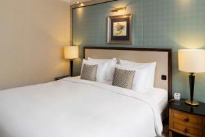 a large white bed in a hotel room with two lamps at Kempinski Hotel Corvinus Budapest in Budapest