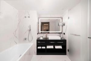 a bathroom with a sink and a tub and a mirror at Kempinski Hotel Corvinus Budapest in Budapest