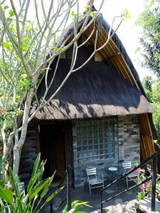 a hut with a thatched roof and chairs in front of it at Omah Pakem in Pakem