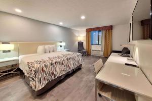 a hotel room with a bed and a desk at Travelodge by Wyndham Indianapolis Speedway in Indianapolis