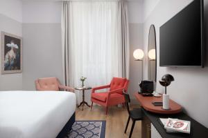 a hotel room with a bed and a desk and chair at Anglo American Hotel Florence, Curio Collection By Hilton in Florence