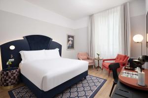 um quarto de hotel com uma cama e uma secretária e um quarto em Anglo American Hotel Florence, Curio Collection By Hilton em Florença