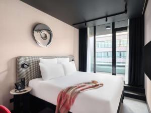 um quarto de hotel com uma cama branca e um espelho em TRIBE Budapest Stadium em Budapeste