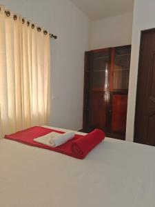 coperta rossa su un letto in una camera di Timber Monk Beach Resort a Pallipuram