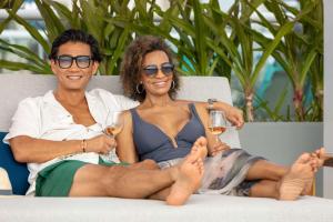 a man and woman sitting on a couch with glasses of wine at Hilton Cancun Mar Caribe All-Inclusive Resort in Cancún