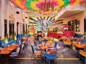 a restaurant with wooden tables and chairs and a mural at Novotel Living Bangkok Sukhumvit Legacy in Bangkok