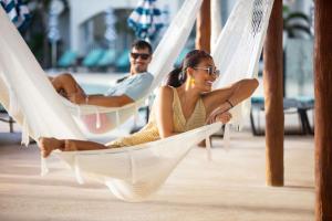 two people sitting in hammocks at a resort at Hilton Cancun Mar Caribe All-Inclusive Resort in Cancún