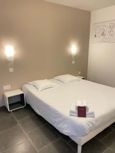 a bedroom with a large bed with a book on it at Hôtel Némo Aéroport de Pau - KB HOTEL GROUP in Sauvagnon