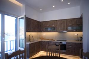 a kitchen with wooden cabinets and a large window at Onar Loutra, Kythnos in Loutra