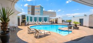 einen Pool mit Stühlen und ein Gebäude in der Unterkunft Meikles Hotel in Harare