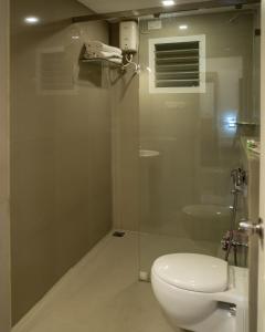 a bathroom with a toilet and a glass shower stall at La Woods Village Resort in Tiruvannāmalai +39 photos