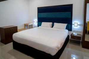 a bedroom with a large white bed with a blue headboard at La Woods Village Resort in Tiruvannāmalai