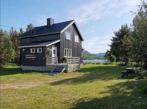 a black house on a grass field with a picnic table at Villa Skoganvarre in Skoganvarre