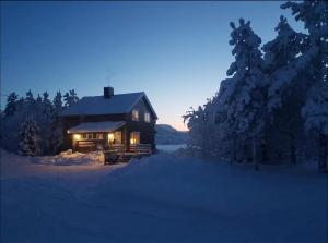 una cabaña de madera en la nieve por la noche en Villa Skoganvarre, en Skoganvarre