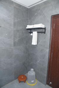uma casa de banho com uma parede em azulejo, uma prateleira e toalhas em HOTEL LAWANG SIGNAGE em Deoghar