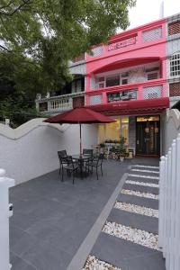 a pink building with a patio with tables and an umbrella at Qing Noise Villas in Hualien City