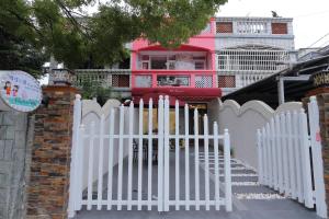 a white fence in front of a pink house at Qing Noise Villas in Hualien City