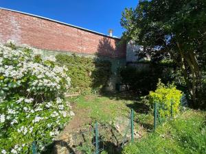 eine Ziegelmauer mit weißen Blumen neben einem Zaun in der Unterkunft COROLLE Whole flat with garden near Paris in Vitry-sur-Seine